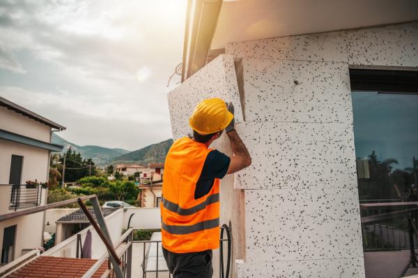 Engineer fitting polystyrene thermal cladding for energy-saving measures on a house.